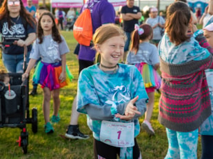 Girls on the Run participant and coach smile while running at 5K celebration